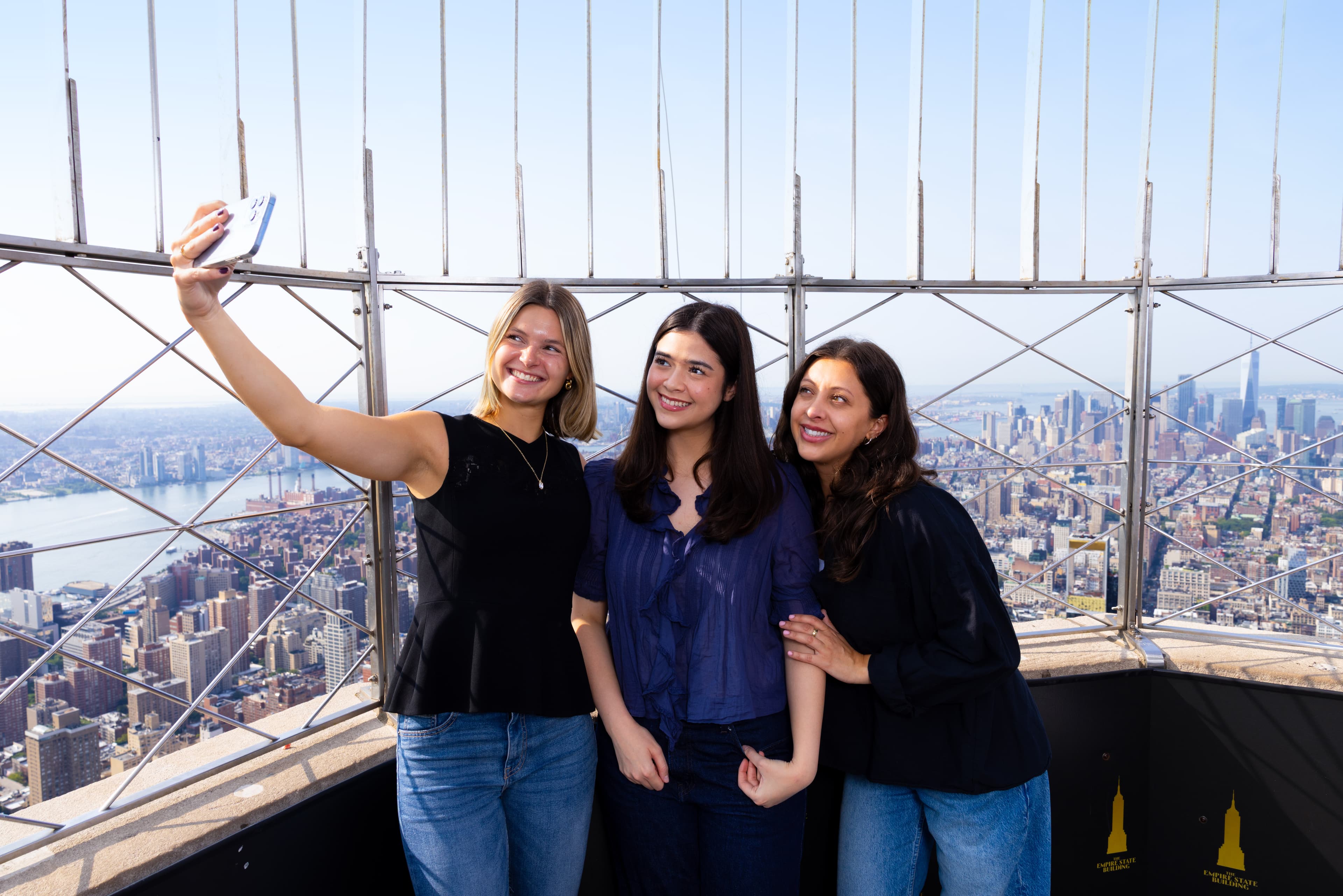 Three girls taking a selfie with NYC's best view of manhattan in the background