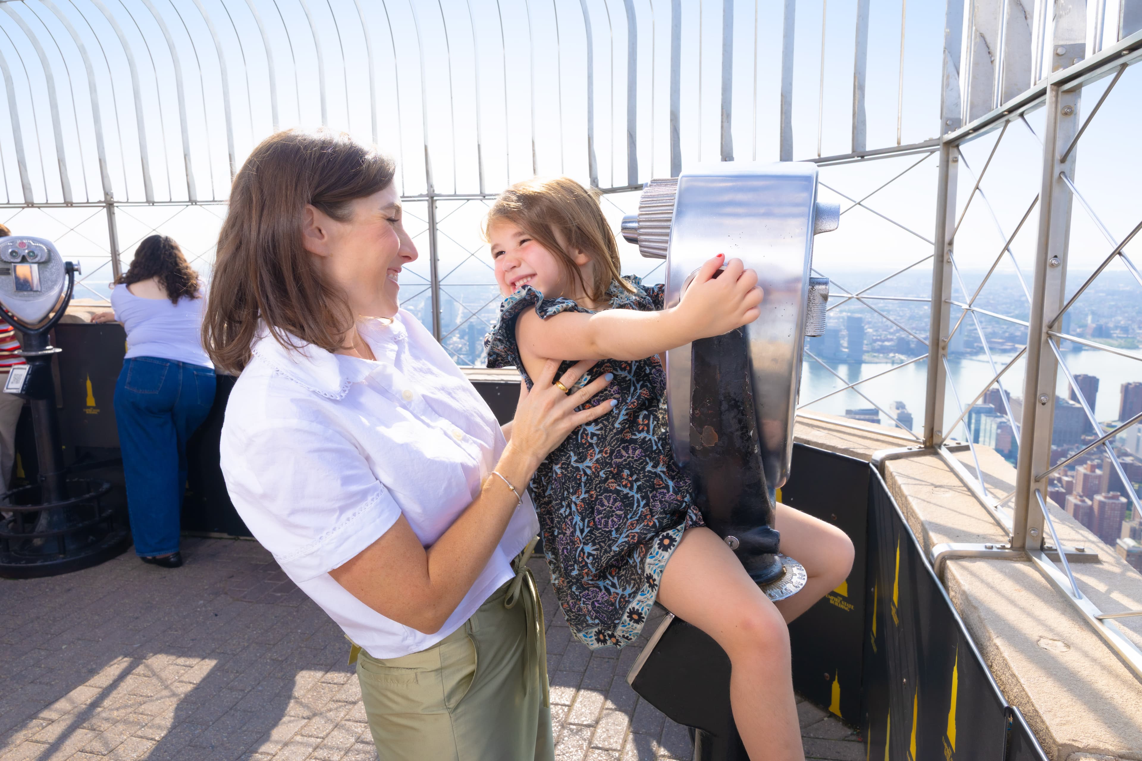 Mother and her child using a viewfinder from NYC's best attraction, the Empire State Building Observation Deck