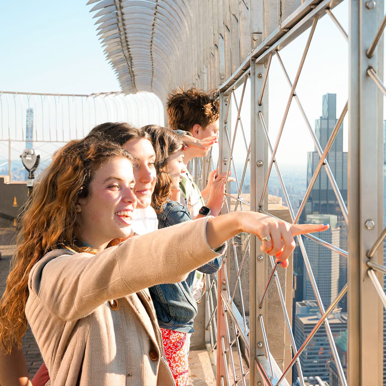 A group of teenagers look out at the view from the 86th floor observation deck of the Empire State Building