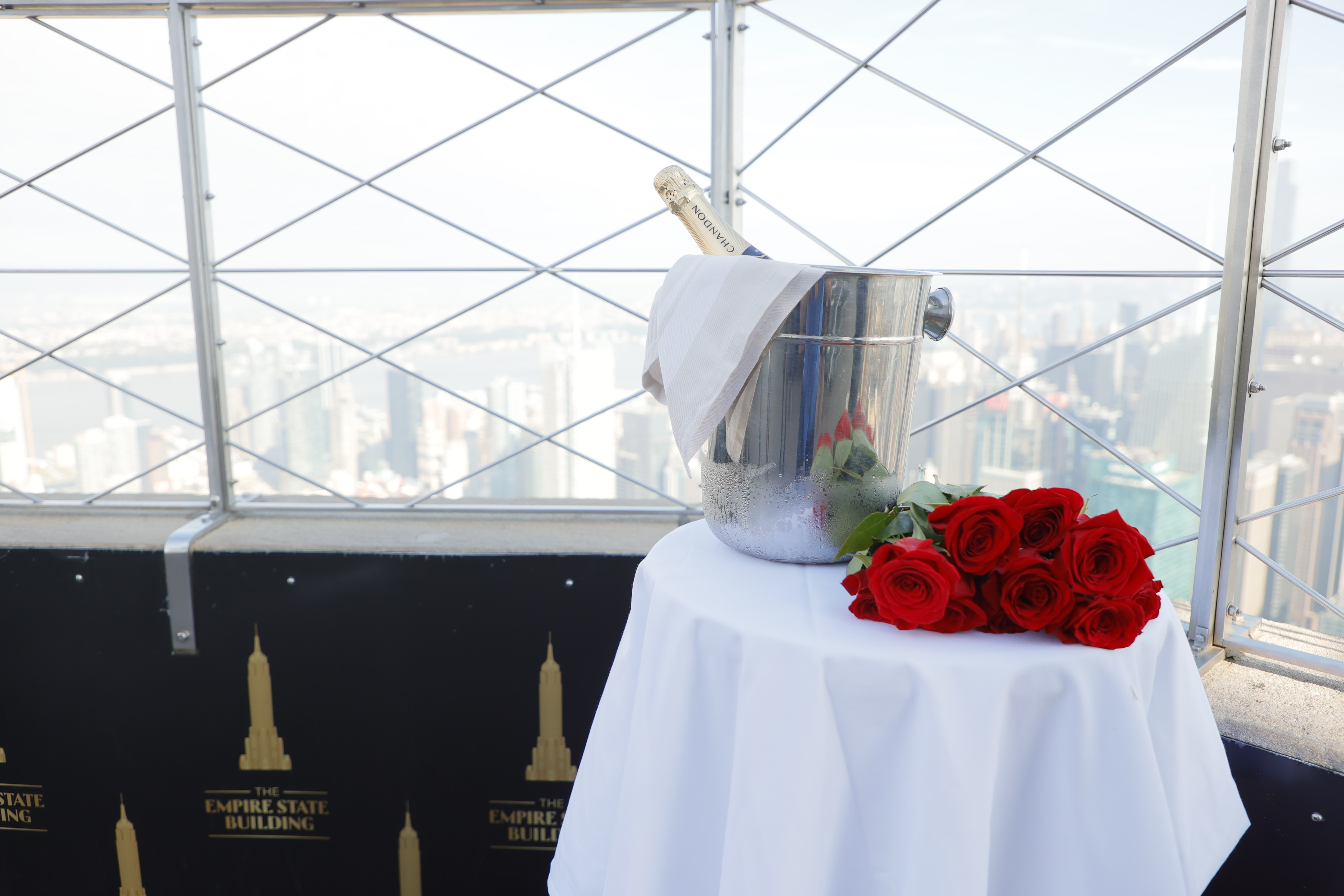 Des roses et une bouteille de champagne dans un seau à glace sur une table au sommet de l'Empire State Building