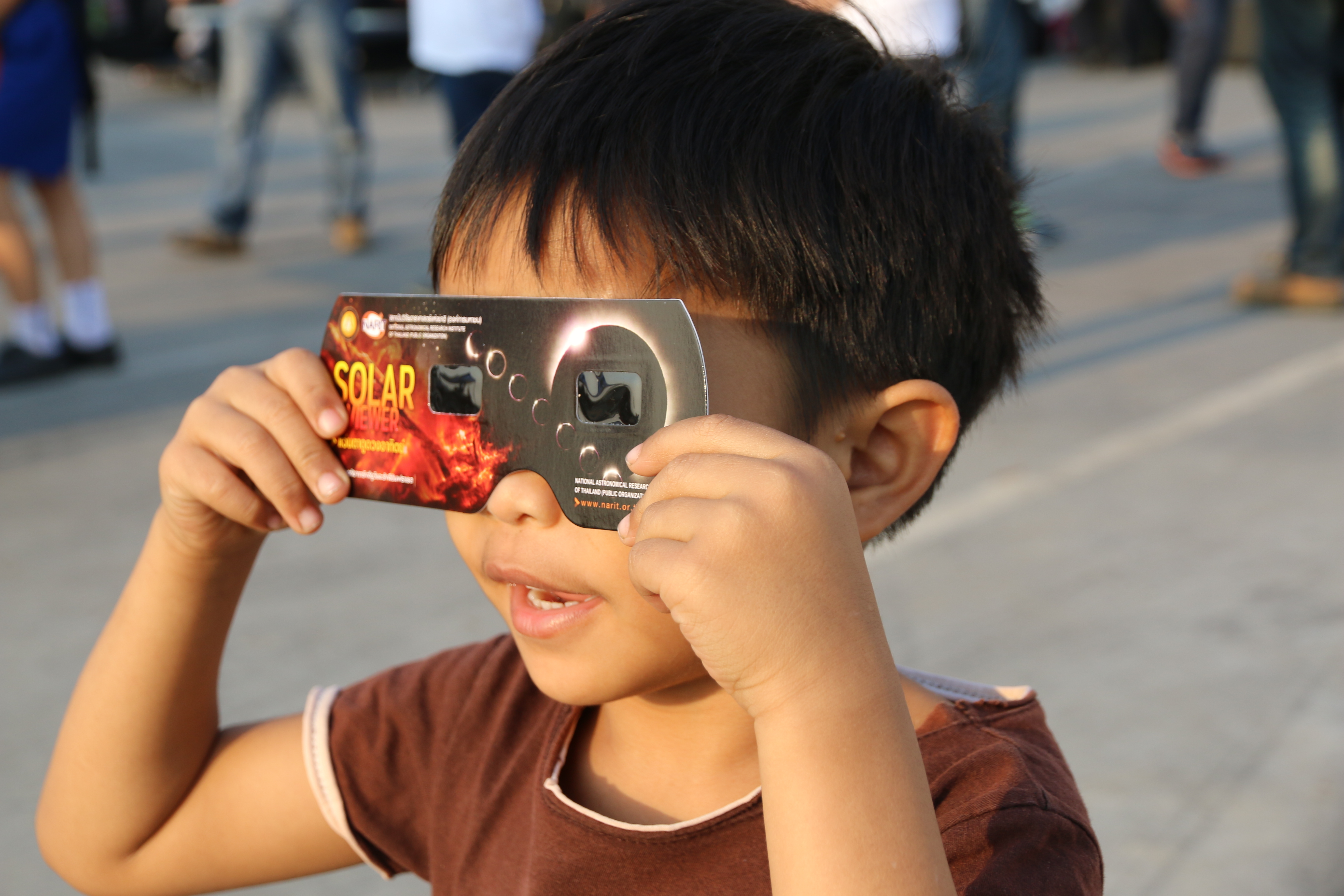 A child looking at a solar eclipse through eclipse glasses
