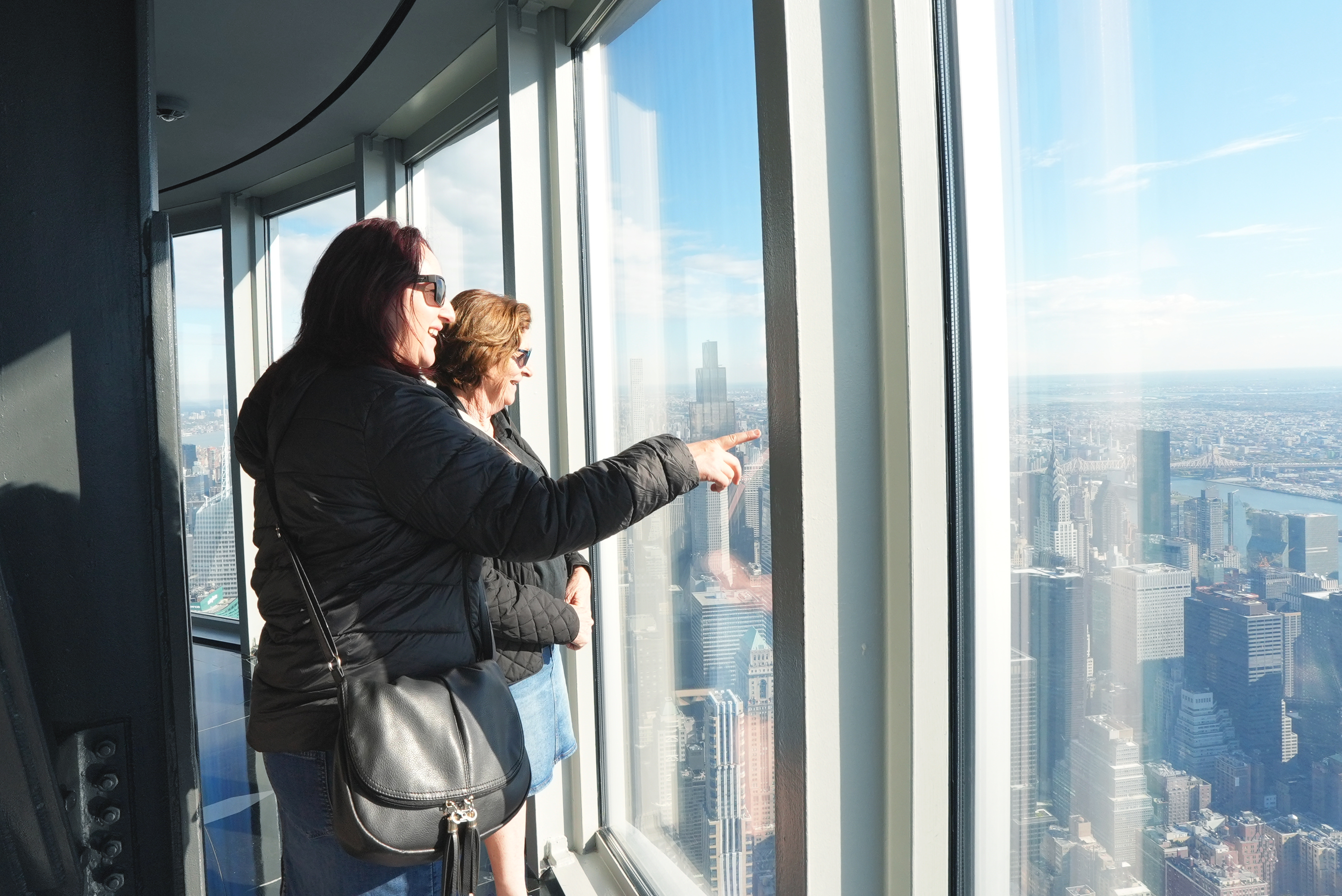 Two women on the 102nd Floor Observatory pointing and looking at the view