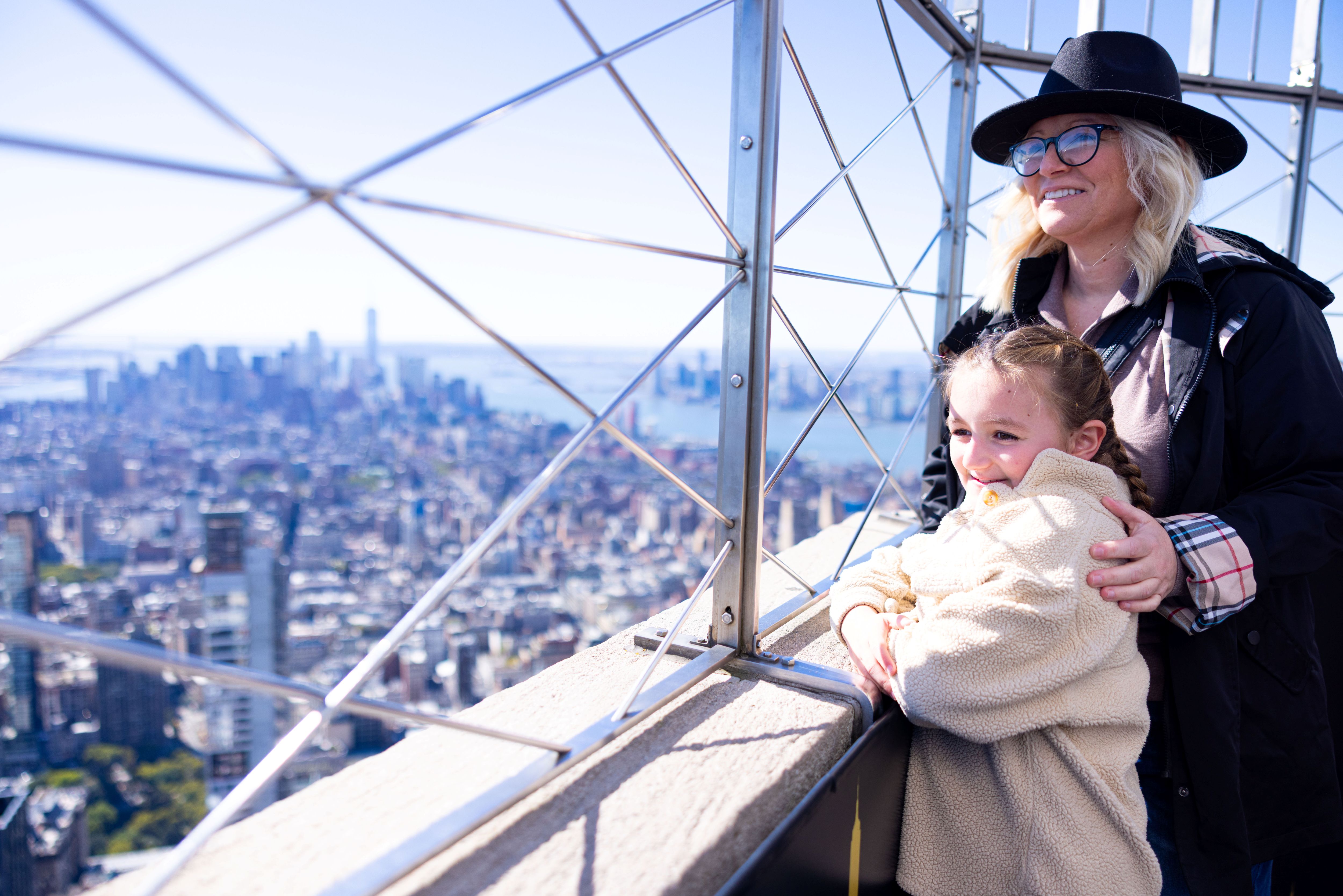 People looking out at NYC from the 86th floor observation deck at the Empire State Building Observatory.