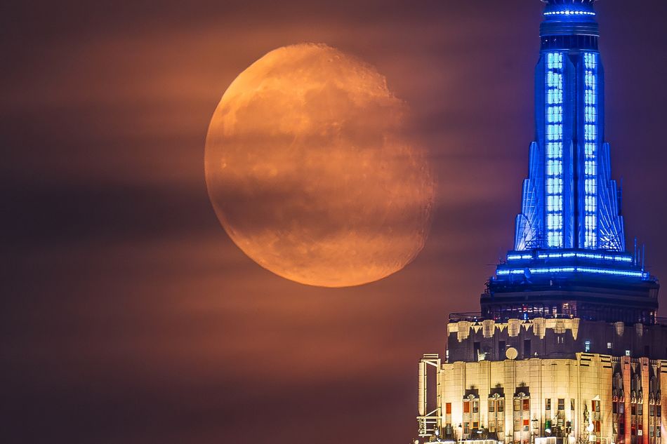The moon next to the Empire State Building lit in red, white, and blue.