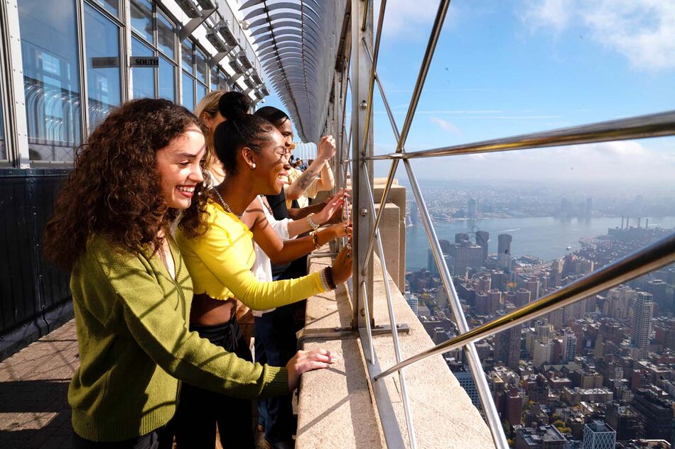 People observing the view from the 86th floor open air observation deck at the Empire State Building Observatory experience.