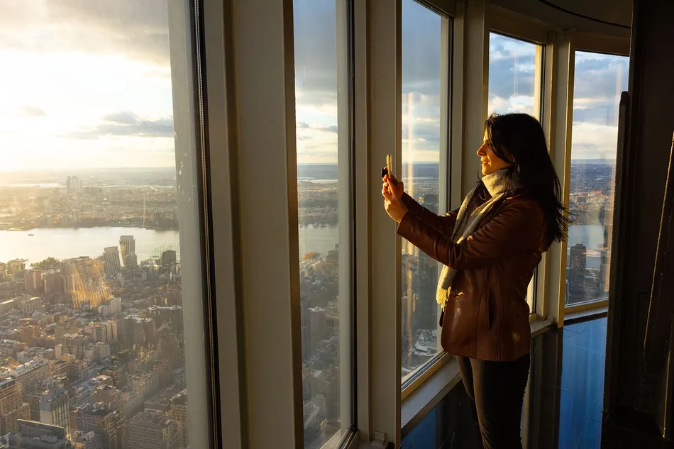 Woman taking a photo of the view from the 102nd Floor of the Empire State Building Observatory