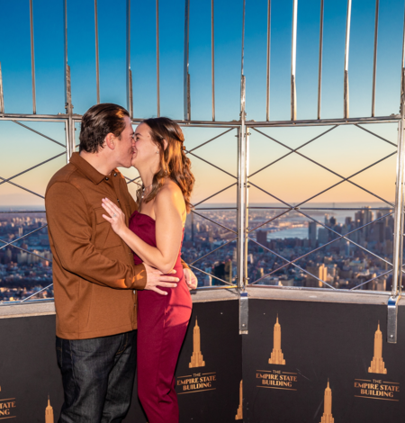 Pareja besándose en un área privada en la cima del Empire State Building al atardecer