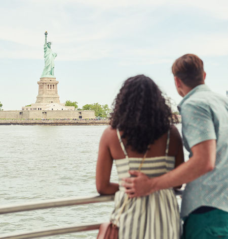 un homme et une femme regardent la statue de la liberté