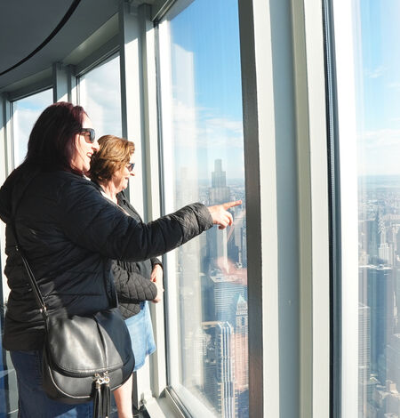 Two women on the 102nd Floor Observatory pointing and looking at the view