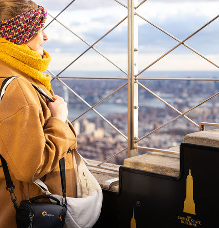 Woman looking out at NYC from the 86th floor observation deck at the Empire State Building Observatory.