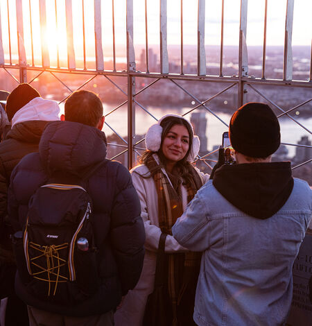 People looking out at NYC from the 86th floor observation deck at the Empire State Building Observatory.
