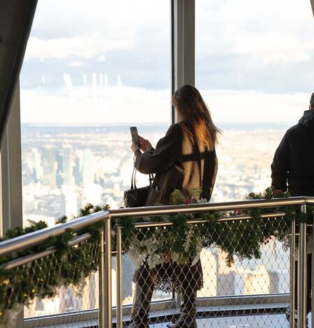 Woman taking photo on the Empire State Building 102nd Floor Observatory with holiday decorations