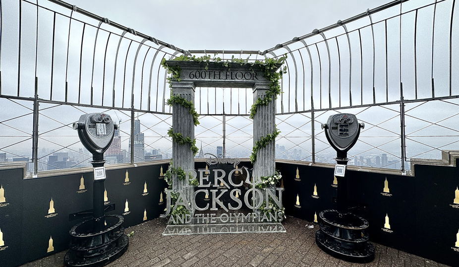the terrace of 86th floor of the Empire State Building with a big Percy Jackson signboard decorated with two small pillars and green vines