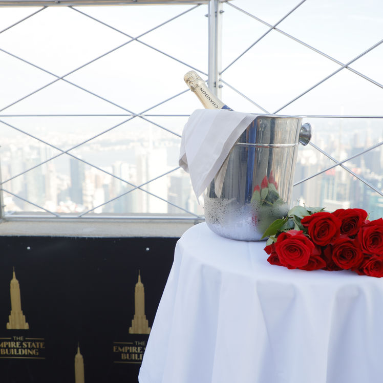 Des roses et une bouteille de champagne dans un seau à glace sur une table au sommet de l'Empire State Building