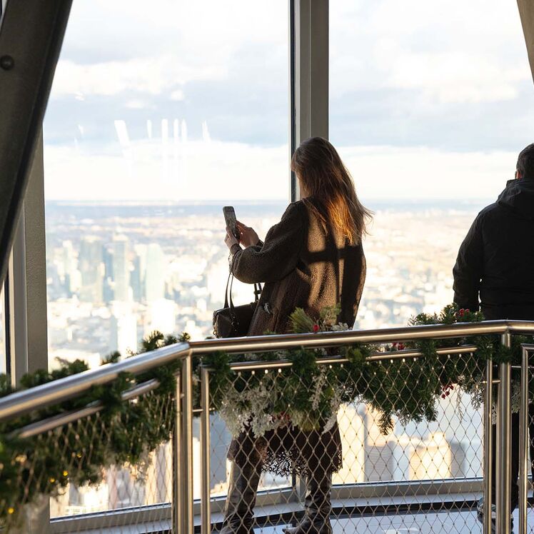 Woman taking photo on the Empire State Building 102nd Floor Observatory with holiday decorations