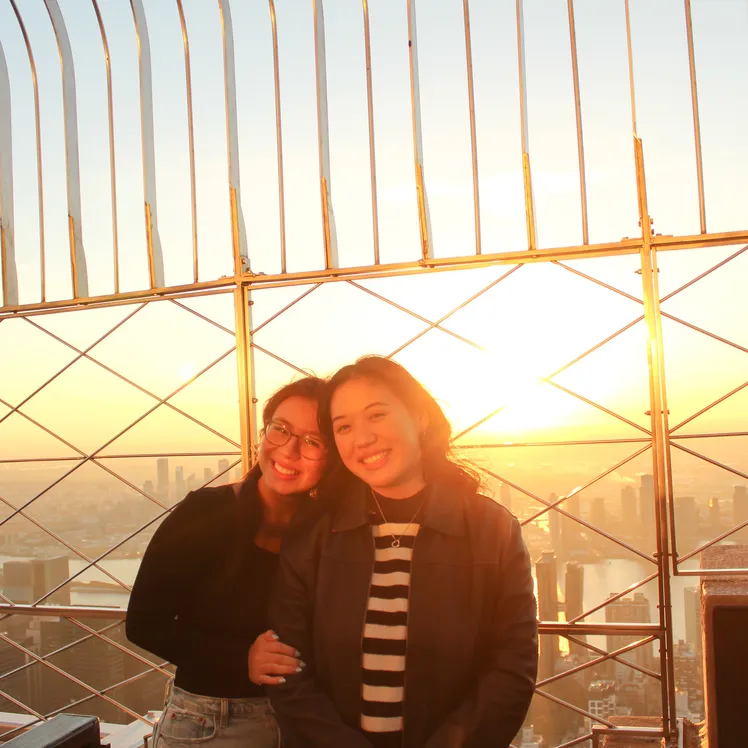 Two girls smiling for a photo on the 86th Floor Observation Deck at the Empire State Building Observatory