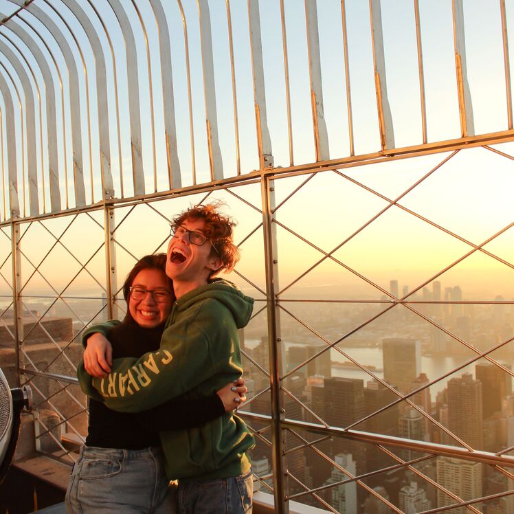 People looking out at NYC from the 86th floor observation deck at the Empire State Building Observatory.