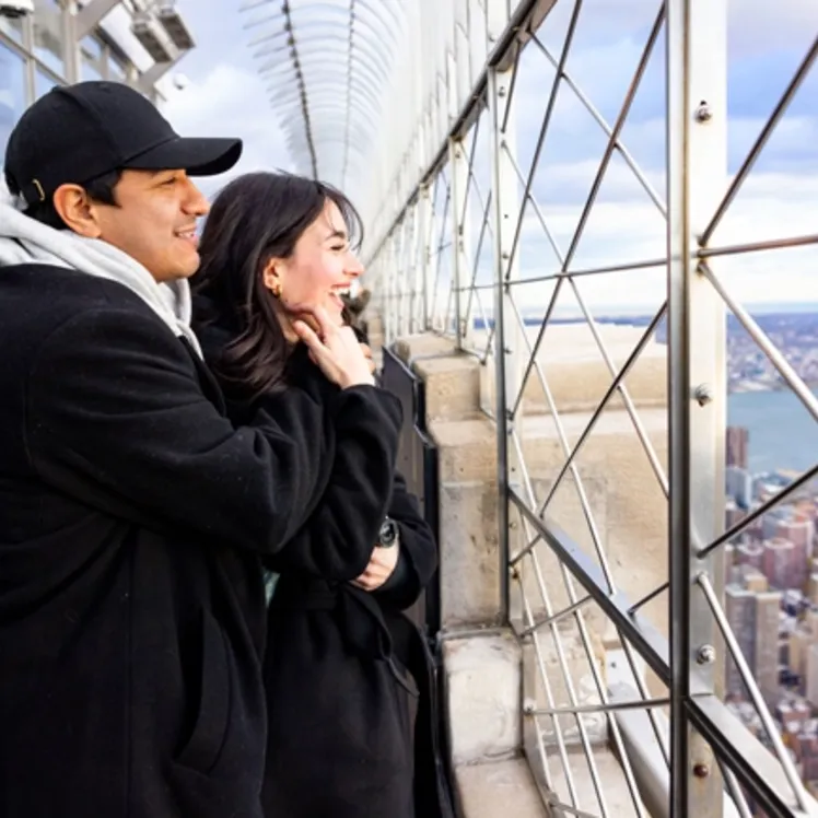 Couple at the Empire State Building's 86th Floor looking out to 360 degree views of Manhattan