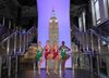The Rockettes pose at the two-story building model.